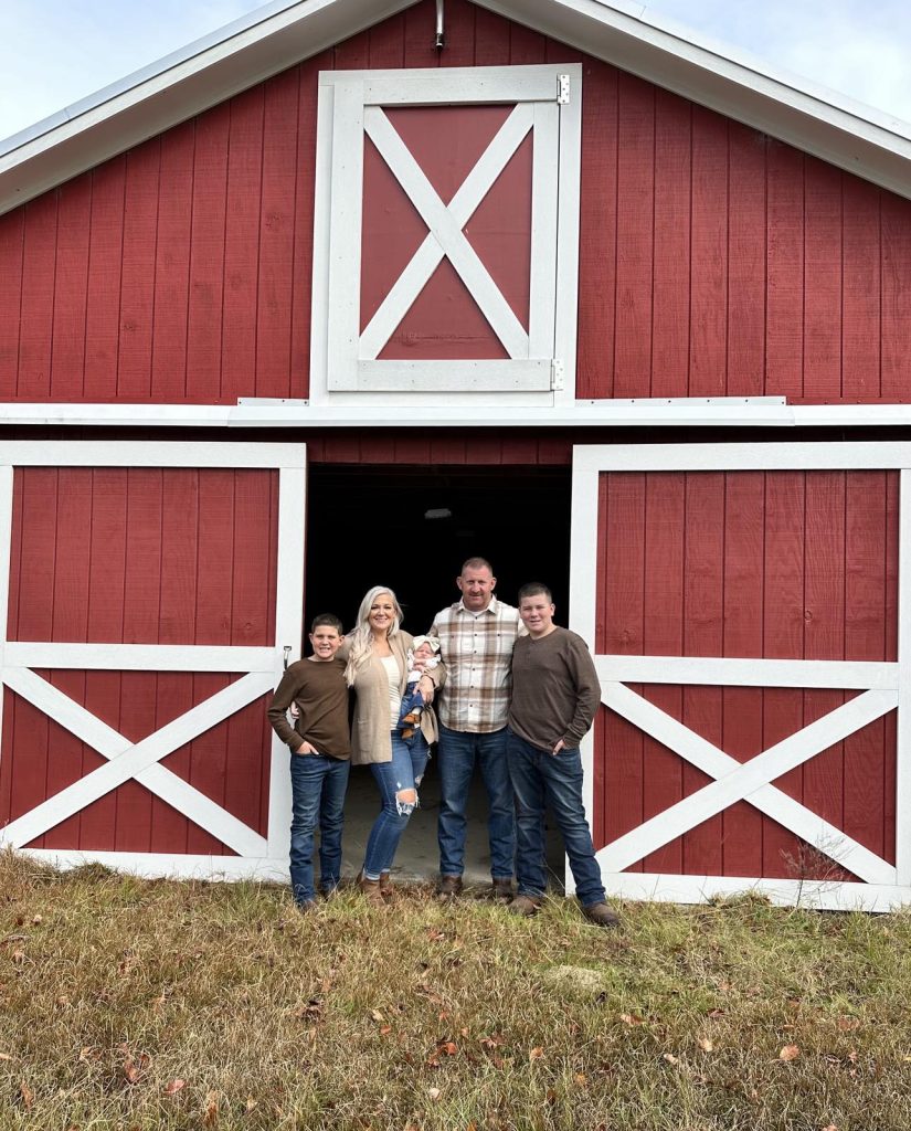 a family in front of a barn