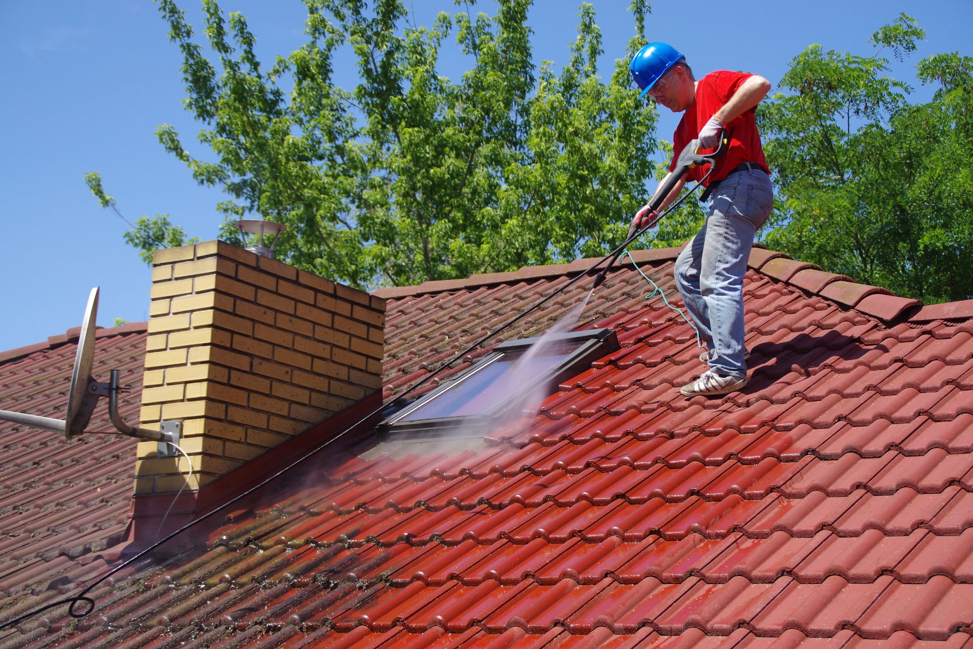 A man cleans the roof with pressure cleaning